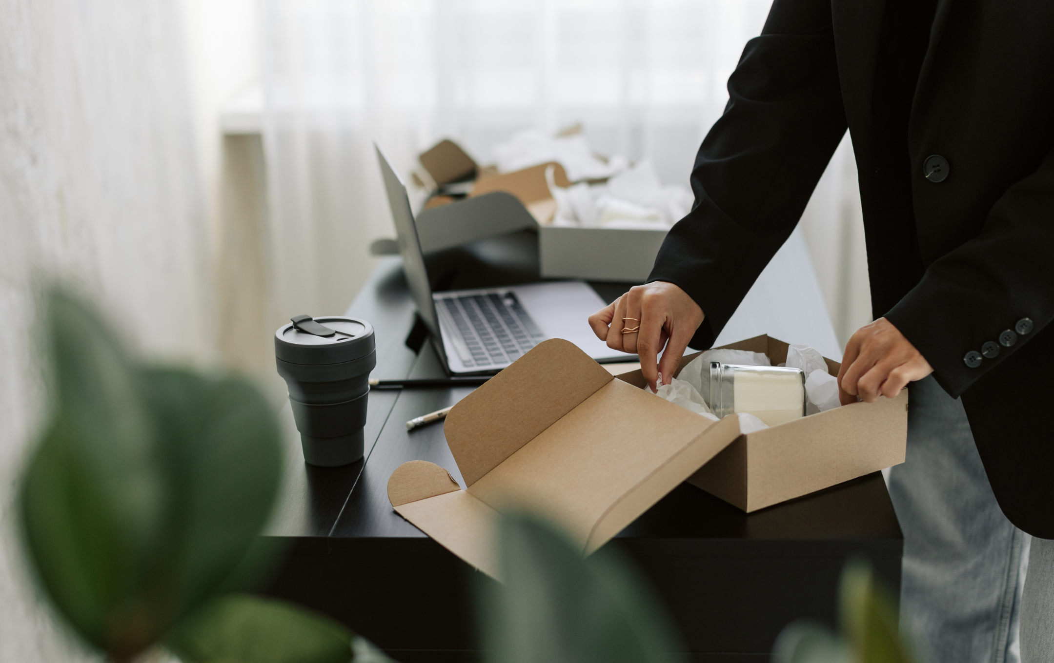 En person packar ner en glasburk i en flyttkartong.